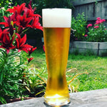 Glass of beer on a wooden surface with flowers in the background