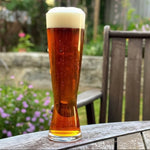 Glass of beer on a wooden table with a garden background