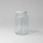 Clear glass jar with a white lid on a light gray background