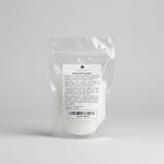 A clear plastic stand-up pouch containing white Epsom salt, with a white label showing the text 'MAGNESIUM SULPHATE' and 'Epsom Salts', photographed on a neutral light gray background.